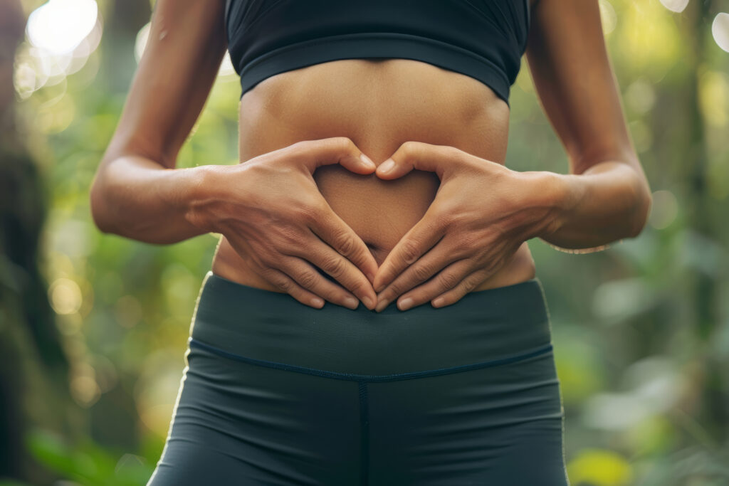 Fit person creating a heart with their hands on their stomach.