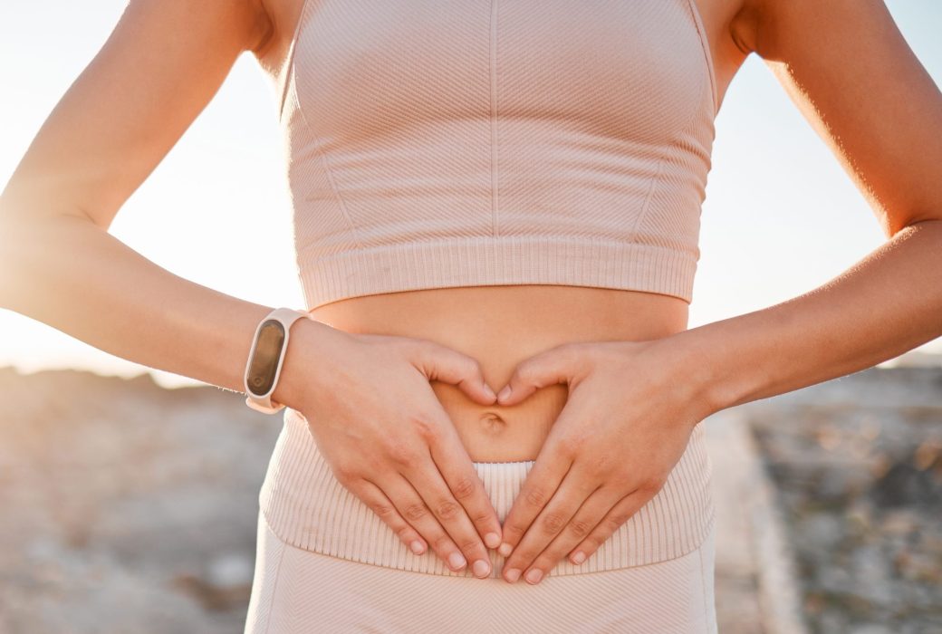 Woman, heart and hands on stomach for fitness, weightloss diet or holistic gut wellness. Closeup female abdomen, love fingers or belly emoji of body digestion, skincare and healthy exercise in nature.